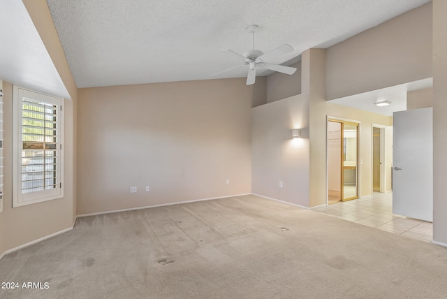 spare room featuring ceiling fan, high vaulted ceiling, a textured ceiling, and light carpet