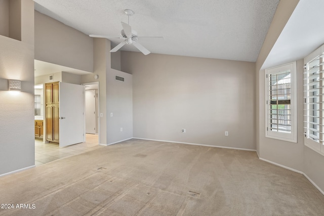 carpeted empty room with ceiling fan, a textured ceiling, and high vaulted ceiling