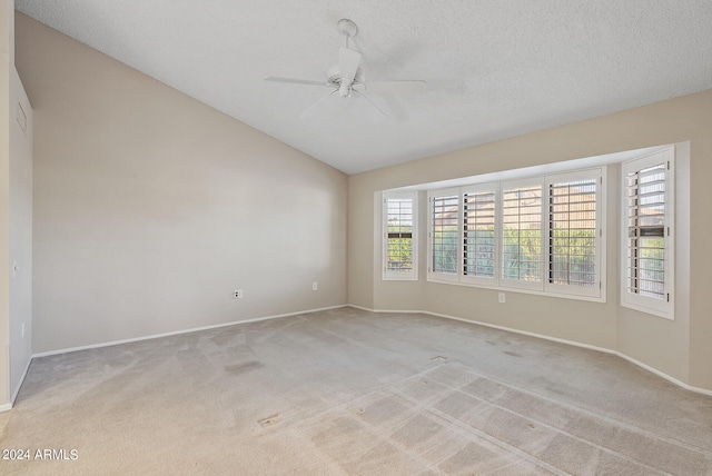 carpeted empty room featuring lofted ceiling, ceiling fan, and a textured ceiling