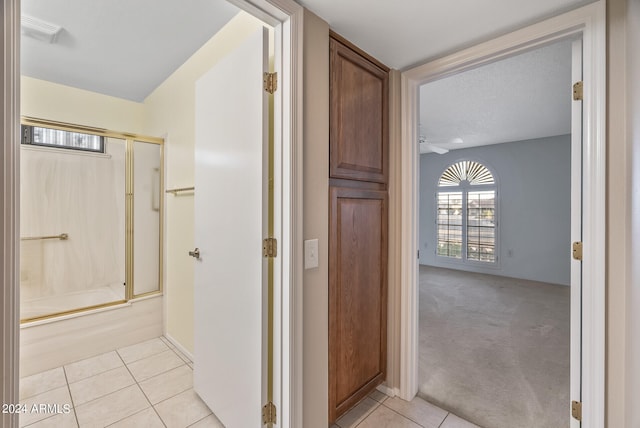 bathroom with a textured ceiling, tile patterned floors, and enclosed tub / shower combo