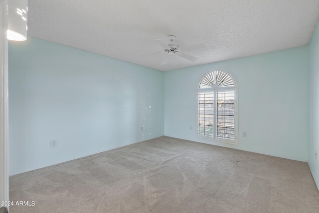 carpeted empty room featuring ceiling fan and a textured ceiling