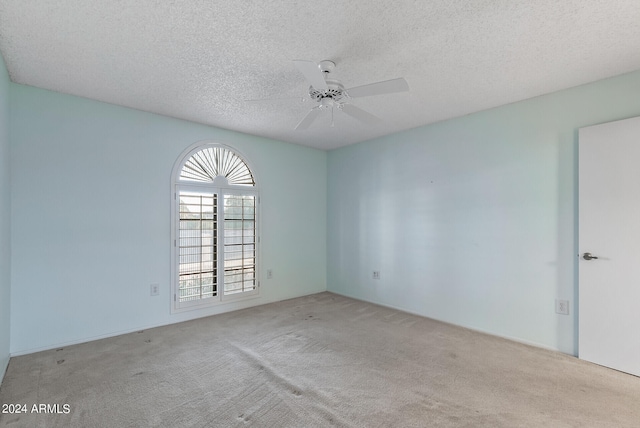 empty room featuring light carpet, a textured ceiling, and ceiling fan