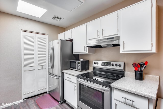 kitchen featuring white cabinets, a skylight, stainless steel appliances, and dark wood-type flooring