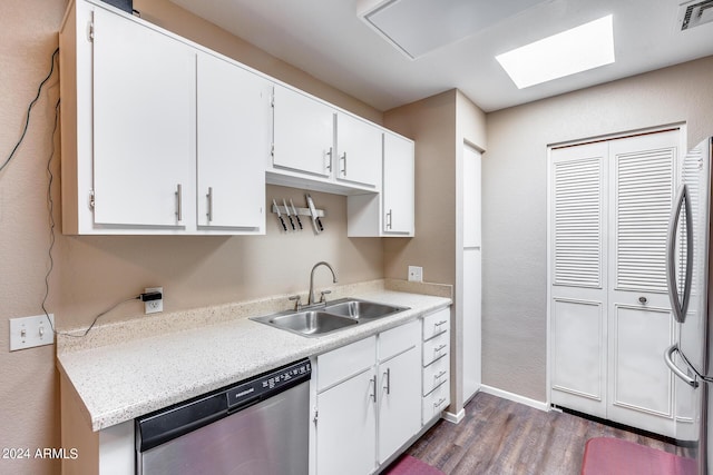 kitchen with a skylight, white cabinetry, sink, stainless steel appliances, and dark hardwood / wood-style flooring