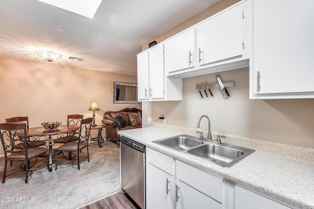 kitchen with stainless steel dishwasher, white cabinets, sink, and a textured ceiling