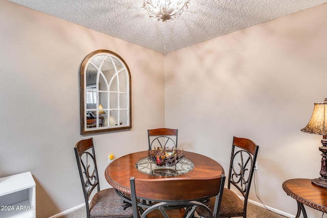 dining area featuring carpet flooring, a textured ceiling, and a notable chandelier