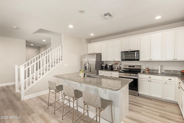 263 N Wilson Dr, Chandler, AZ 85225 - kitchen with appliances with stainless steel finishes, recessed lighting, a kitchen island with sink, light stone counters, and light wood-style floors
