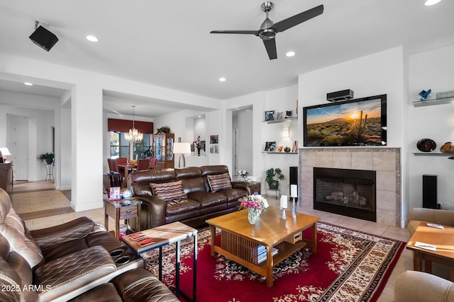 tiled living room featuring a fireplace and ceiling fan with notable chandelier