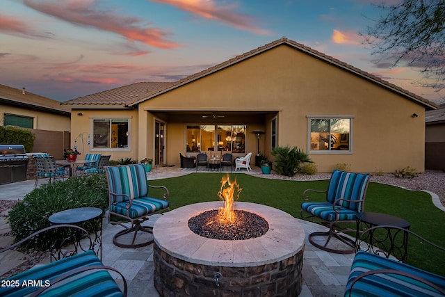 back house at dusk featuring a patio and an outdoor fire pit