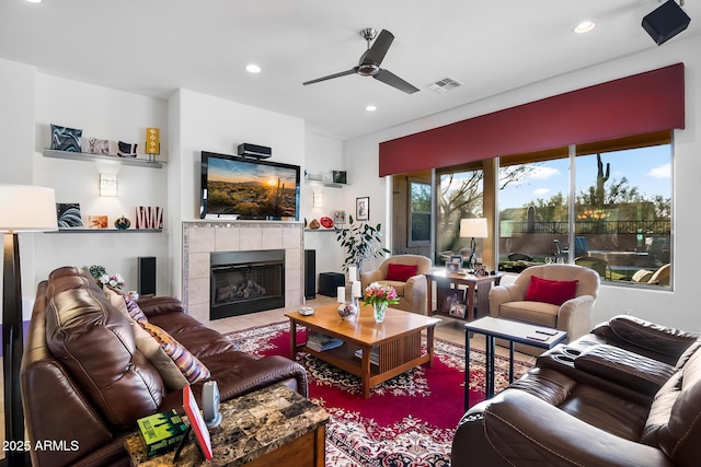 living room with a tile fireplace and ceiling fan