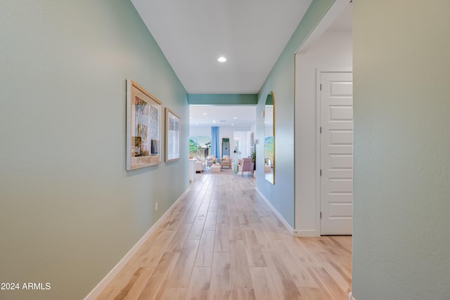 corridor featuring recessed lighting, baseboards, arched walkways, and light wood finished floors