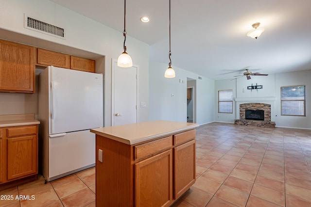 2421 W Indigo Dr, Chandler, AZ 85248 - kitchen with freestanding refrigerator, ceiling fan, light tile patterned floors, a stone fireplace, and pendant lighting