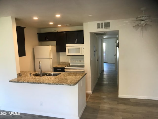 kitchen featuring white appliances, ceiling fan, light stone countertops, dark hardwood / wood-style flooring, and kitchen peninsula