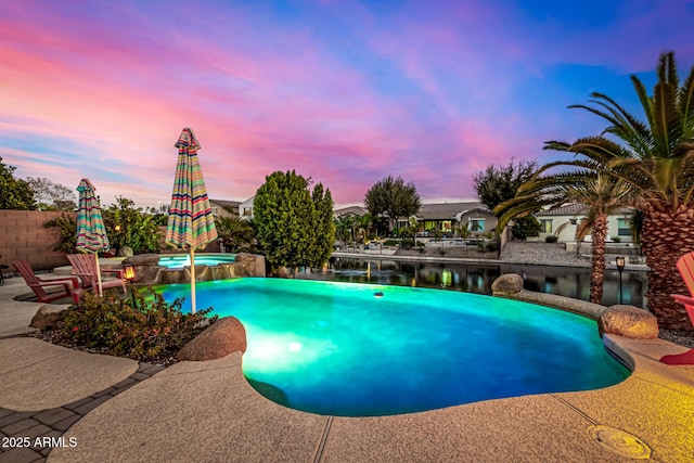 pool at dusk featuring a patio area and a water view