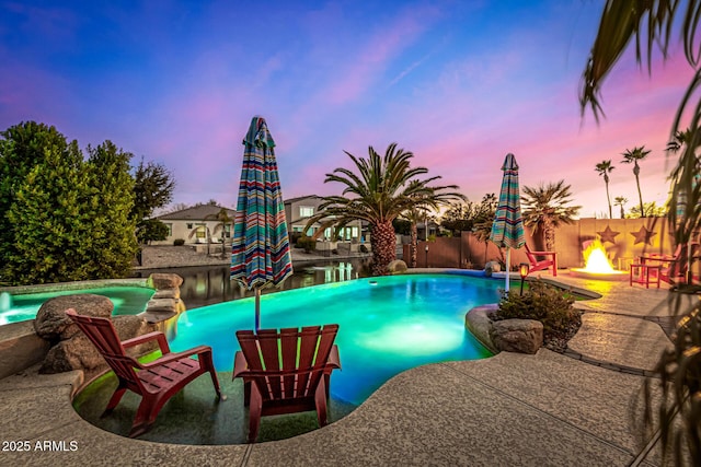 pool at dusk with a patio and a fire pit