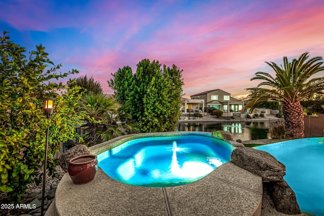 pool at dusk featuring a water view