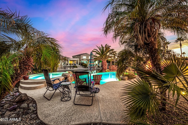 pool at dusk featuring a patio area