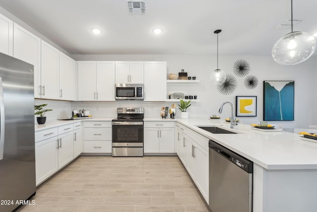 kitchen with kitchen peninsula, appliances with stainless steel finishes, sink, white cabinets, and hanging light fixtures