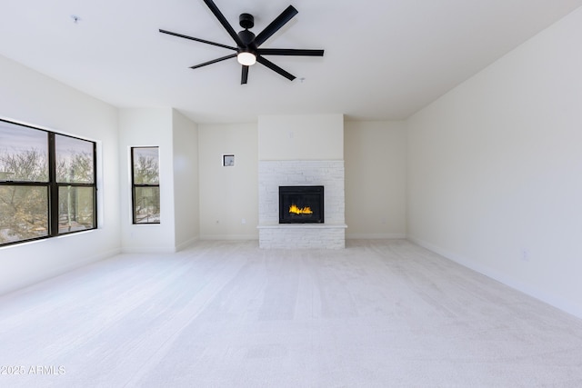 unfurnished living room with ceiling fan, light colored carpet, and a brick fireplace