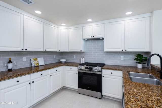 kitchen featuring stainless steel gas stove, sink, white cabinetry, and dark stone countertops