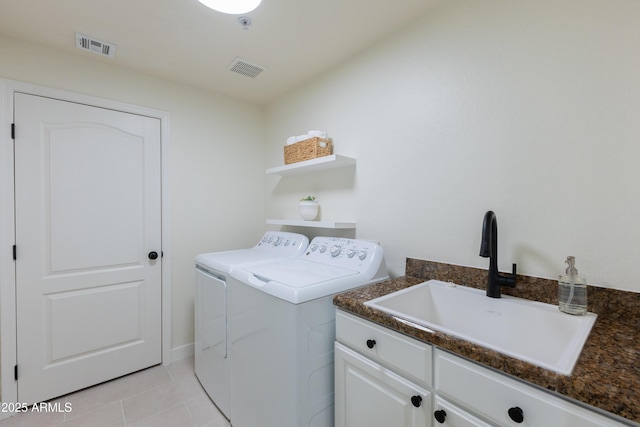 clothes washing area featuring sink, washing machine and clothes dryer, cabinets, and light tile patterned flooring