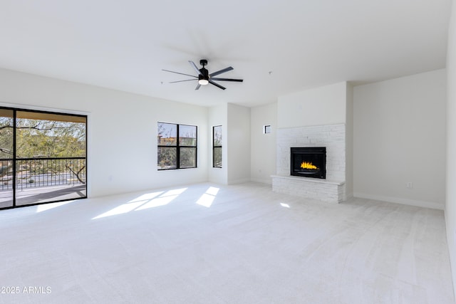 unfurnished living room with a brick fireplace, light colored carpet, and ceiling fan