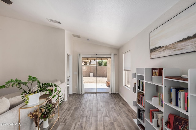 living area with hardwood / wood-style flooring, lofted ceiling, and a textured ceiling