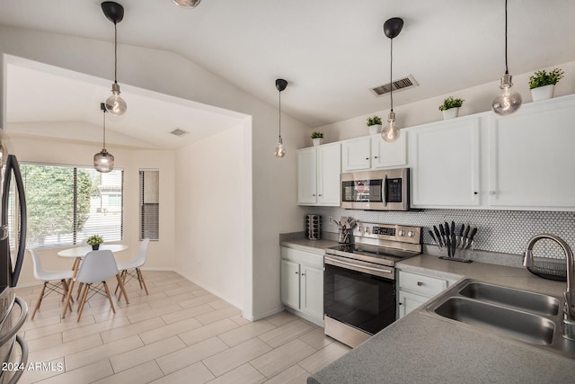 kitchen featuring white cabinets, stainless steel appliances, lofted ceiling, decorative light fixtures, and sink