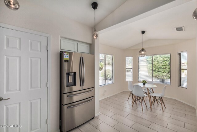 kitchen with lofted ceiling, stainless steel refrigerator with ice dispenser, and hanging light fixtures