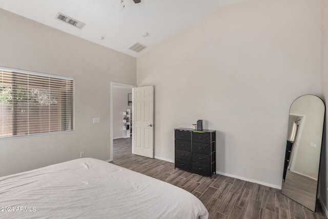 bedroom with high vaulted ceiling and dark wood-type flooring