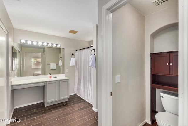 bathroom featuring curtained shower, vanity, and toilet