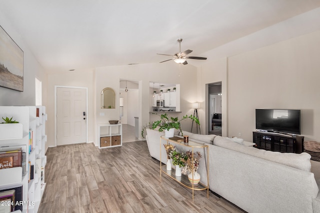 living room with light wood-type flooring, vaulted ceiling, and ceiling fan