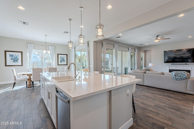 kitchen featuring sink, white cabinetry, dishwasher, an island with sink, and pendant lighting