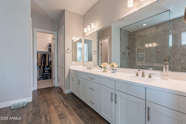 bathroom with a tile shower, vanity, and wood-type flooring