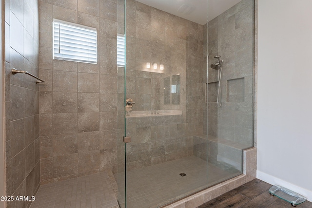 bathroom featuring wood-type flooring and a tile shower