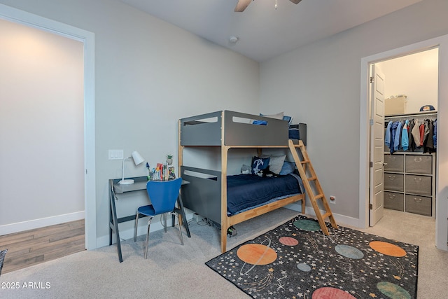 carpeted bedroom with a spacious closet, a closet, and ceiling fan