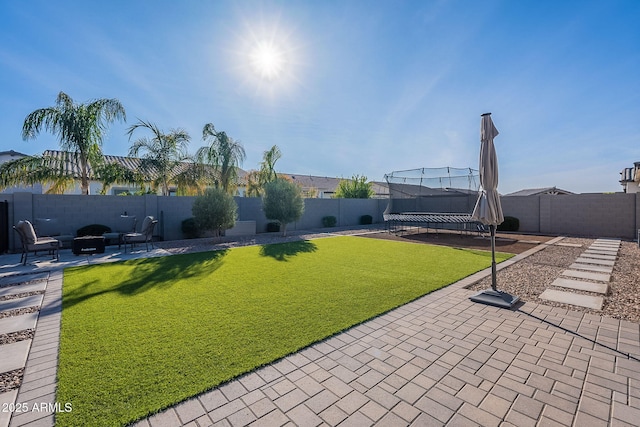 view of yard with an outdoor living space, a patio area, and a trampoline