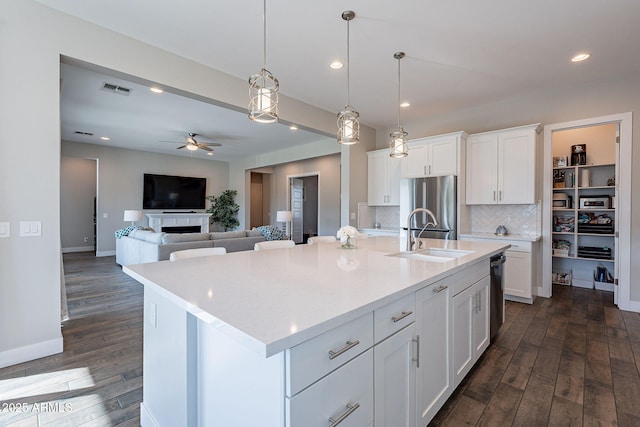 kitchen featuring white cabinetry, sink, a center island with sink, and stainless steel refrigerator