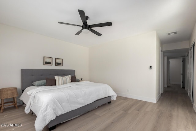 bedroom featuring ceiling fan, light wood-style flooring, visible vents, and baseboards