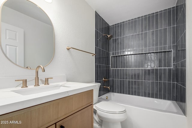 bathroom featuring a textured wall, shower / washtub combination, vanity, and toilet