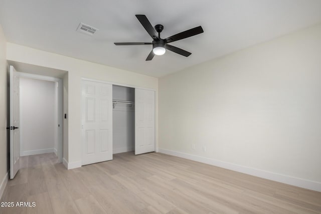 unfurnished bedroom featuring light wood finished floors, baseboards, visible vents, and a closet