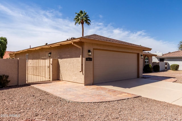 ranch-style house featuring concrete driveway, an attached garage, a gate, and stucco siding