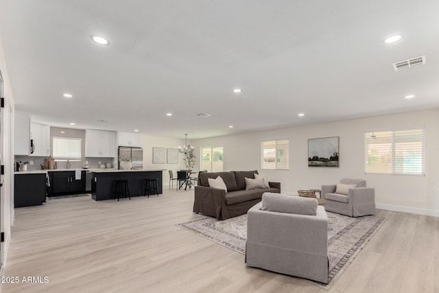 living room featuring light wood-style flooring, visible vents, a chandelier, and recessed lighting