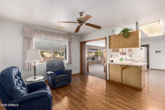 living area featuring light wood finished floors, baseboards, visible vents, and a ceiling fan