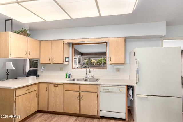kitchen featuring white appliances, a sink, and light brown cabinets