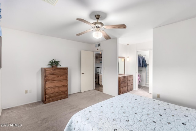 bedroom with visible vents, a spacious closet, a ceiling fan, and light carpet