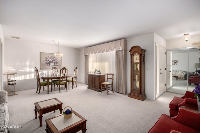 living area featuring carpet floors, visible vents, and a notable chandelier