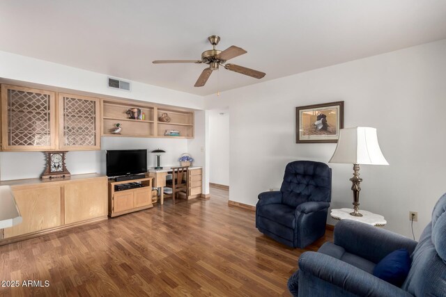 living room with baseboards, visible vents, wood finished floors, and ceiling fan