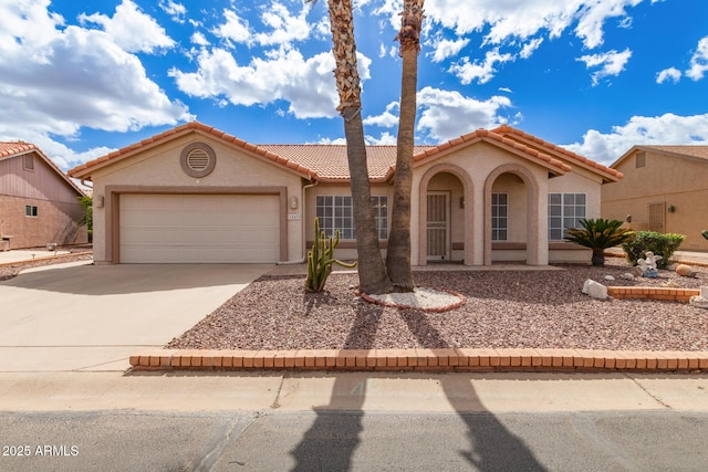 mediterranean / spanish-style house with driveway, an attached garage, a tile roof, and stucco siding