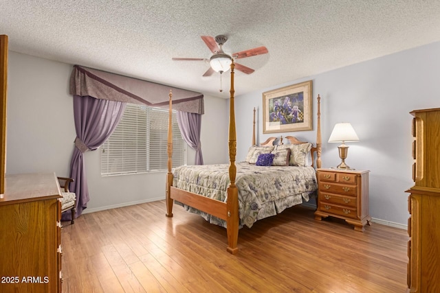 bedroom featuring light wood-type flooring, a ceiling fan, baseboards, and a textured ceiling